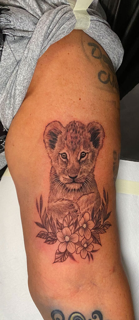 Löwenbaby Tattoo am Oberarm